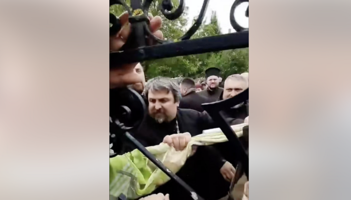 Клирик ПЦУ выламывает калитку на воротах храма УПЦ в Заставне. Фото: СПЖ