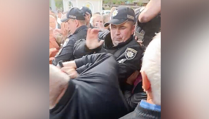 Полицейский применяет силу к прихожанам в Усть-Путиле. Фото: СПЖ