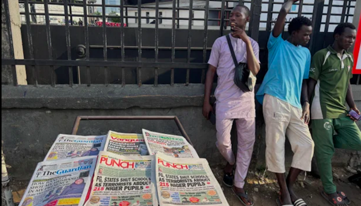 People standing near a display of local newspapers with headlines about the abducted children from school. Photo: Sunday Alamba/AP